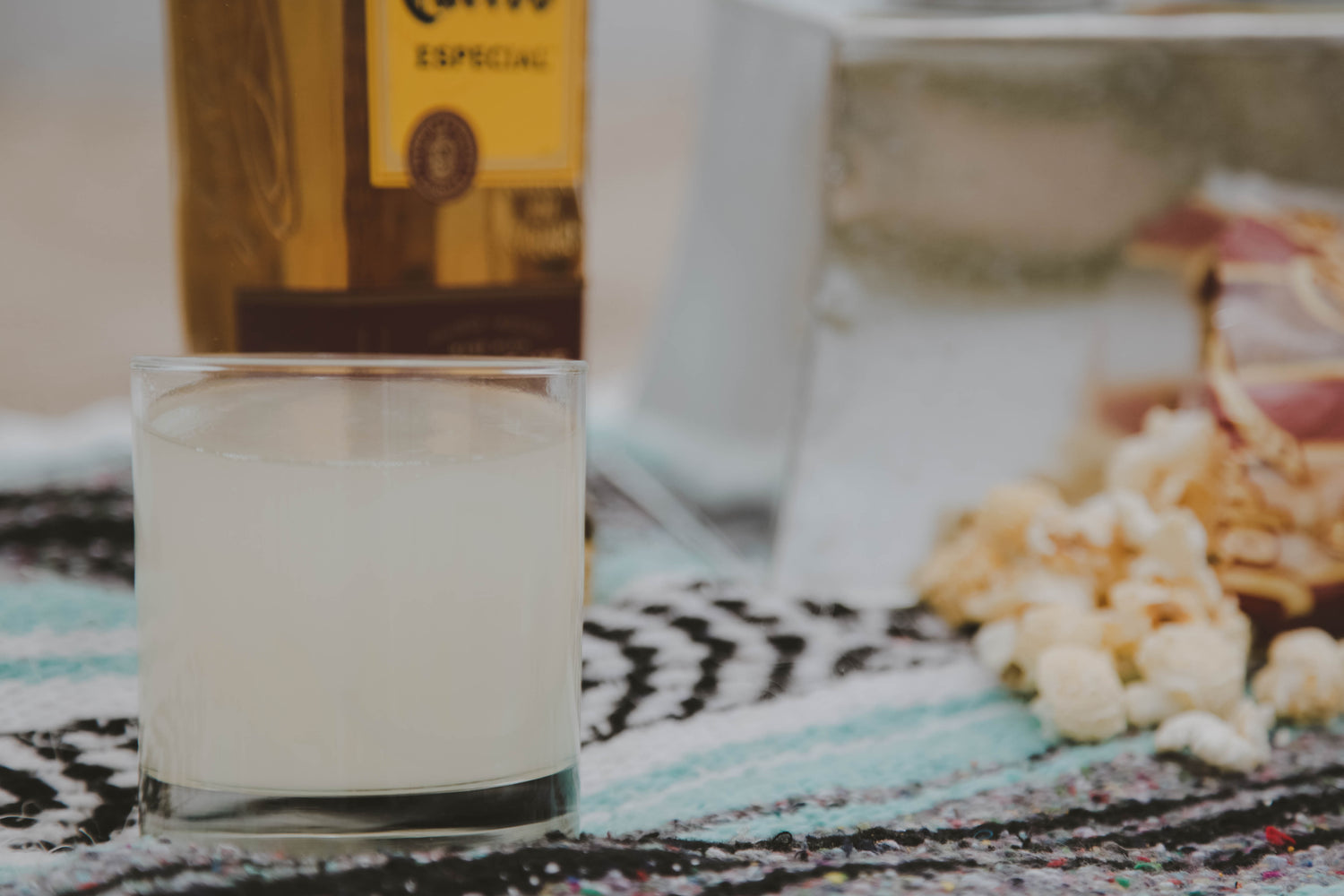 Gift basket from BroBasket, including a glass of cocktail served on a patterned fabric with a tequila bottle and snacks in the background.