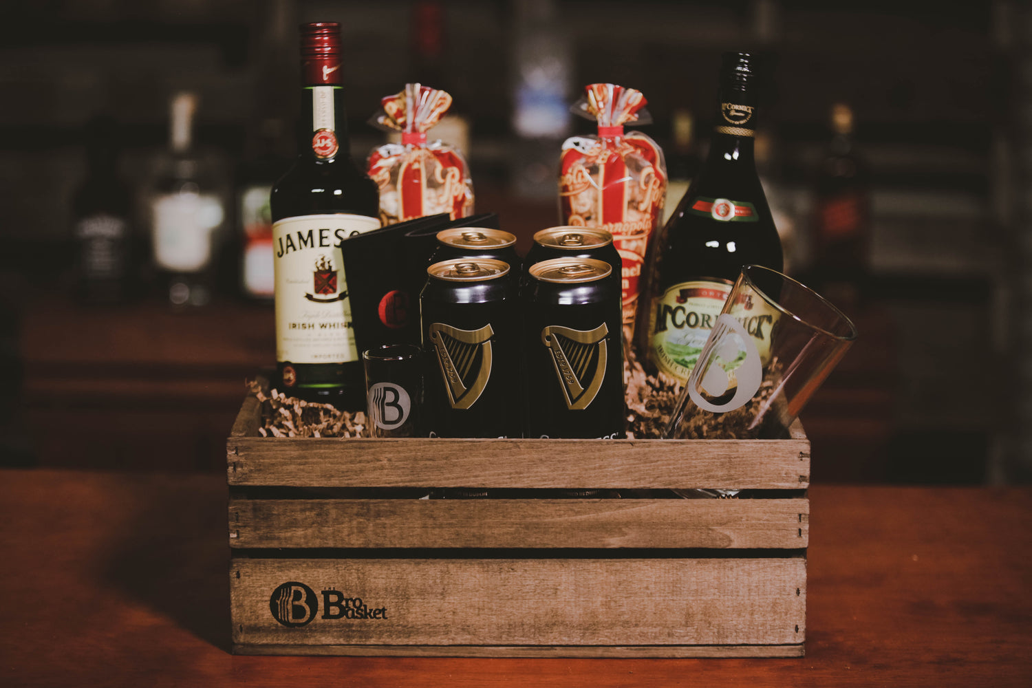 Wooden crate gift set from BroBasket featuring bottles of Irish whiskey, cream liqueur, Guinness beer cans, a branded glass, and packaged snacks.